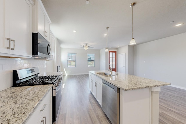 kitchen featuring appliances with stainless steel finishes, backsplash, ceiling fan, baseboards, and light wood-type flooring