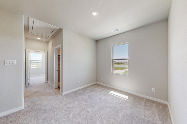 empty room featuring attic access, visible vents, carpet, and baseboards