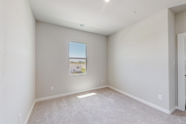 spare room with visible vents, light colored carpet, and baseboards