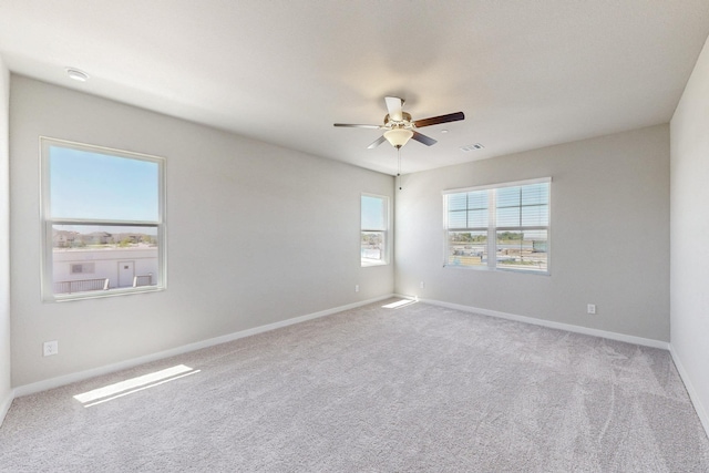 carpeted spare room featuring visible vents, ceiling fan, and baseboards