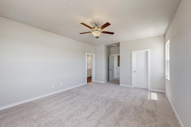 unfurnished bedroom featuring a ceiling fan, ensuite bath, light carpet, and baseboards