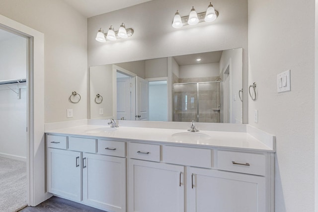 bathroom with double vanity, a shower stall, and a sink