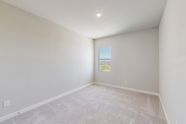 empty room featuring baseboards, recessed lighting, and light colored carpet