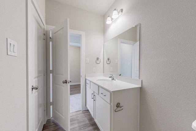 bathroom featuring vanity, a textured wall, and wood finished floors
