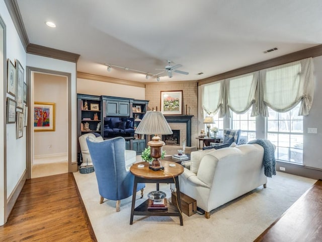 3425 Caleo Ct, Plano, TX 75025 - living room with wood finished floors, ceiling fan, baseboards, ornamental molding, and a brick fireplace