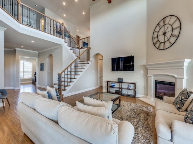 6601 Elderberry Way, Flower Mound, TX 76226 - living area with arched walkways, a high ceiling, stairs, wood finished floors, and crown molding