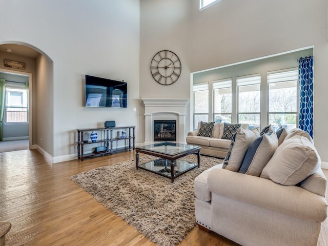6601 Elderberry Way, Flower Mound, TX 76226 - living room featuring arched walkways, baseboards, wood finished floors, a towering ceiling, and plenty of natural light