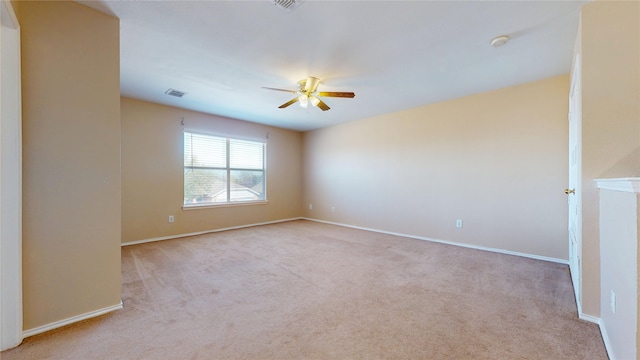 spare room featuring carpet floors, baseboards, a ceiling fan, and visible vents