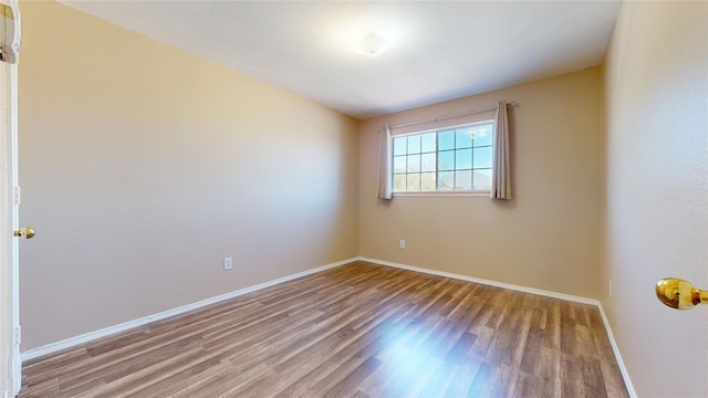 unfurnished room with baseboards and wood finished floors