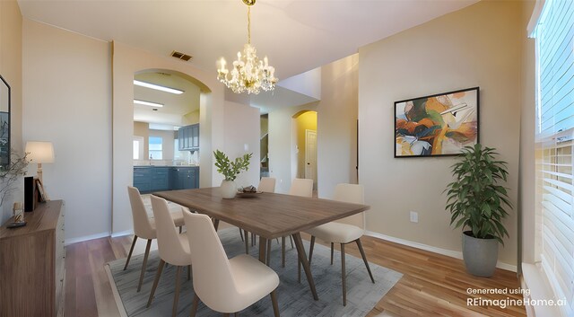 dining space with baseboards, arched walkways, wood finished floors, and a chandelier