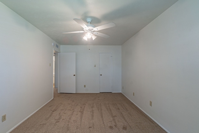 carpeted empty room with baseboards and a ceiling fan