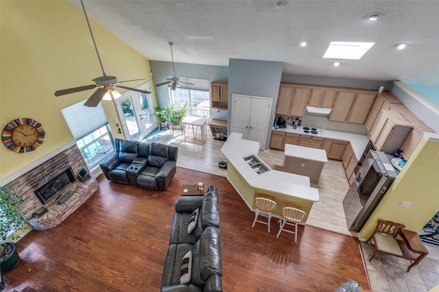 900 Crest Ridge Ct, Irving, TX 75061 - living area featuring vaulted ceiling, light wood finished floors, a brick fireplace, plenty of natural light, and a textured ceiling