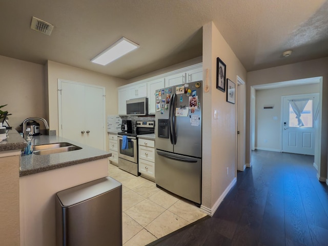 5828 Giddyup Ln, Fort Worth, TX 76179 - kitchen with visible vents, decorative backsplash, appliances with stainless steel finishes, white cabinetry, and a sink