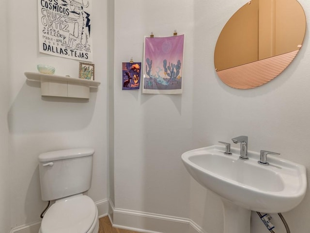 bathroom with a sink, baseboards, and toilet