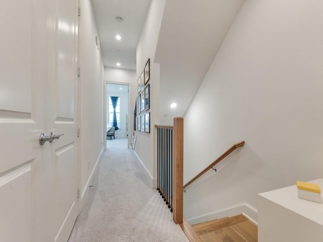 hallway with recessed lighting, baseboards, an upstairs landing, and light carpet
