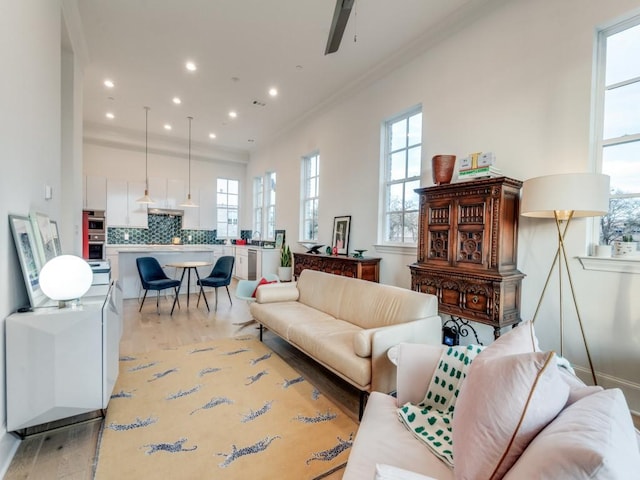 living room with light wood-type flooring, recessed lighting, crown molding, baseboards, and ceiling fan