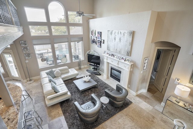 4648 Venetian Way, Frisco, TX 75034 - living room with a fireplace, ceiling fan, a towering ceiling, plenty of natural light, and baseboards