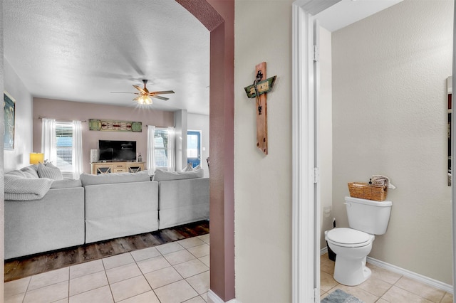1380 Levi Ln, Forney, TX 75126 - living room featuring light tile patterned floors, a ceiling fan, baseboards, arched walkways, and a textured ceiling
