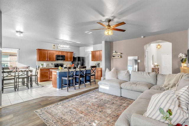 1380 Levi Ln, Forney, TX 75126 - living area with visible vents, a ceiling fan, a textured ceiling, arched walkways, and light wood-style floors