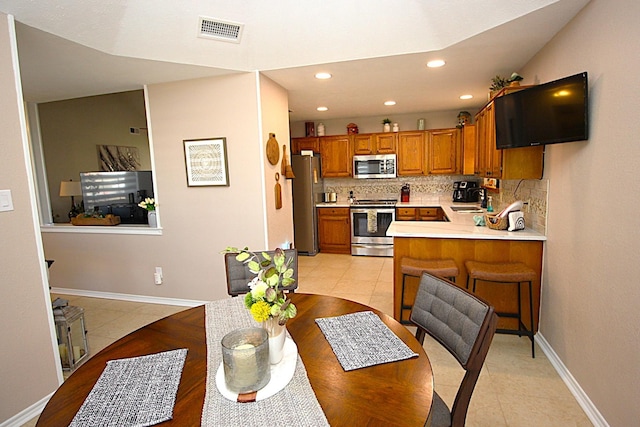510 Canary Ln, Red Oak, TX 75154 - kitchen featuring appliances with stainless steel finishes, brown cabinets, decorative backsplash, light countertops, and light tile patterned floors