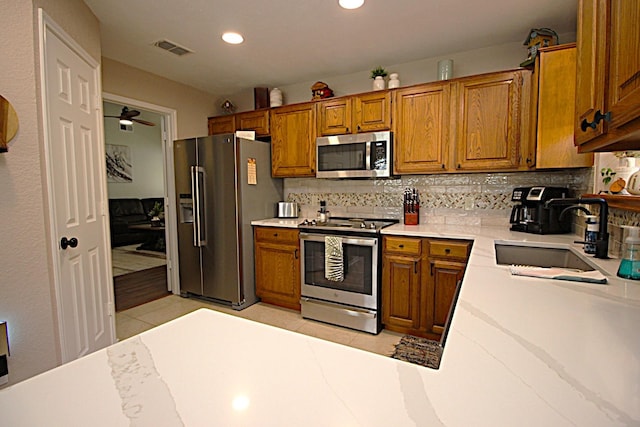 510 Canary Ln, Red Oak, TX 75154 - kitchen featuring stainless steel appliances, a sink, brown cabinets, tasteful backsplash, and recessed lighting