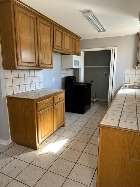 112-114 S Holly Ave, Sherman, TX 75092 - kitchen with tasteful backsplash, tile countertops, light tile patterned floors, brown cabinets, and range