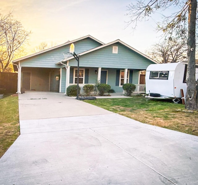 view of front of property with fence, driveway, a front lawn, covered porch, and a carport