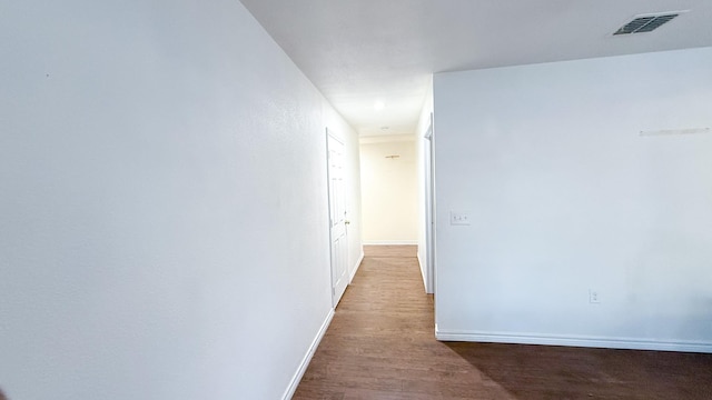 hall with wood finished floors, baseboards, and visible vents