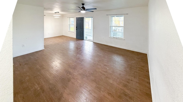 empty room featuring dark wood-style floors, baseboards, and a ceiling fan
