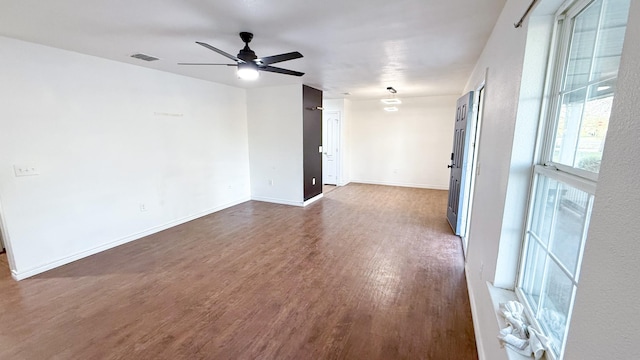 spare room featuring dark wood-style floors, visible vents, ceiling fan, and baseboards