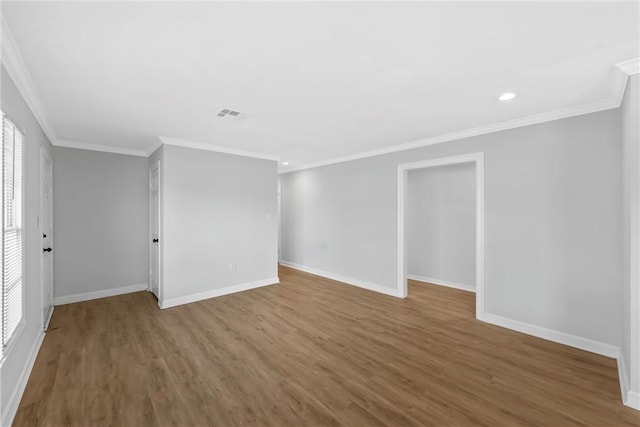 unfurnished room with visible vents, baseboards, wood finished floors, and ornamental molding