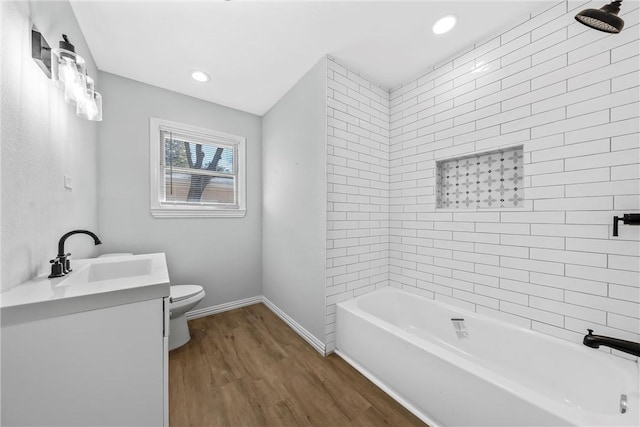 bathroom with vanity, wood finished floors, baseboards, shower / bath combination, and toilet