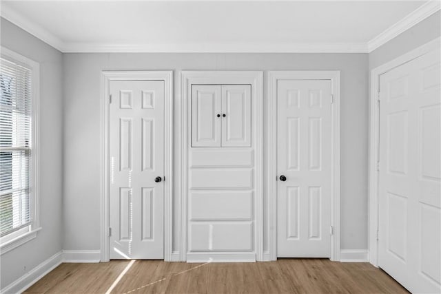 unfurnished bedroom featuring crown molding, wood finished floors, and baseboards