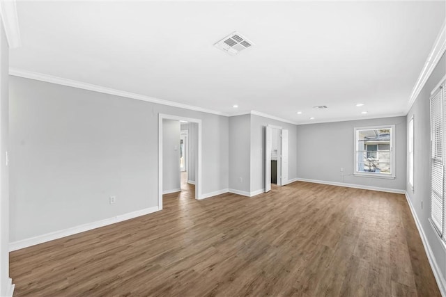 unfurnished living room featuring visible vents, baseboards, wood finished floors, and ornamental molding