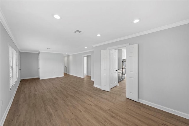 empty room featuring visible vents, ornamental molding, wood finished floors, recessed lighting, and baseboards