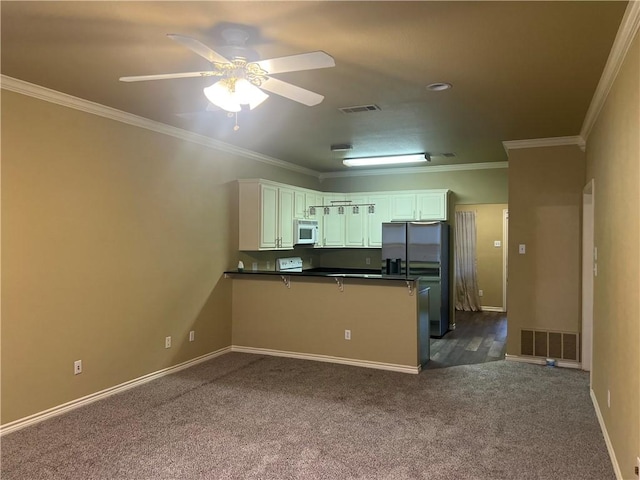 kitchen featuring a peninsula, dark countertops, white microwave, and visible vents