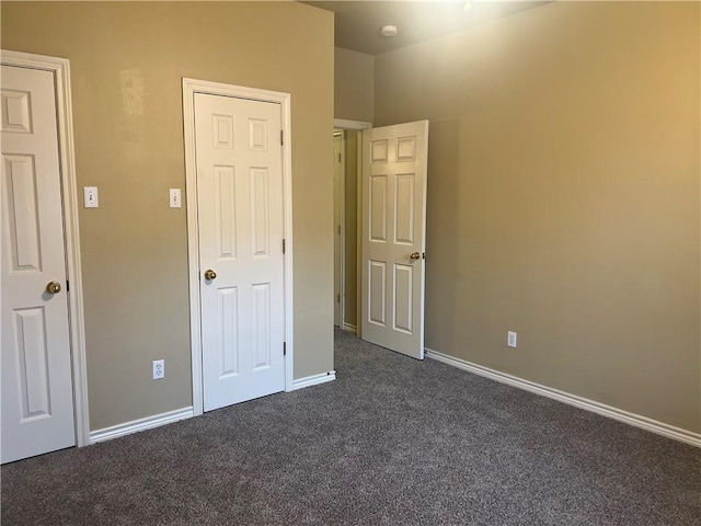 unfurnished bedroom featuring baseboards and dark carpet