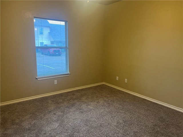 unfurnished room featuring baseboards and dark carpet