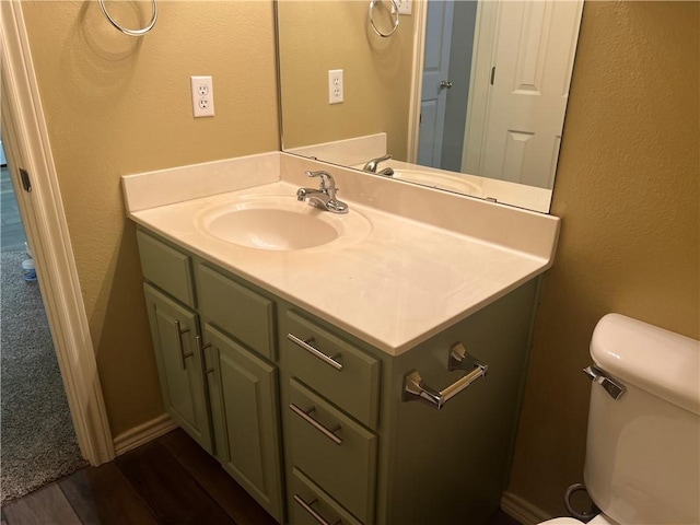 bathroom featuring vanity, toilet, wood finished floors, and a textured wall