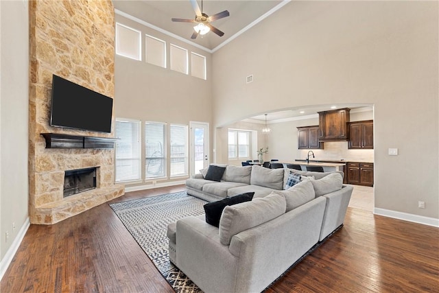 2313 Therese Dr, Waco, TX 76712 - living room with a ceiling fan, baseboards, crown molding, arched walkways, and a fireplace