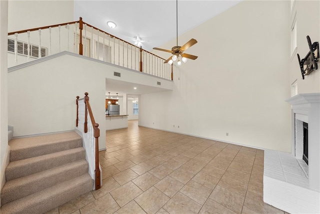 125 Pleasant Grove Ln, Waco, TX 76712 - staircase with tile patterned flooring, visible vents, a fireplace with raised hearth, ceiling fan, and a towering ceiling