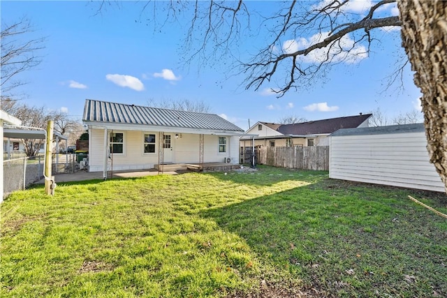 back of house with a fenced backyard, a patio, a lawn, and metal roof