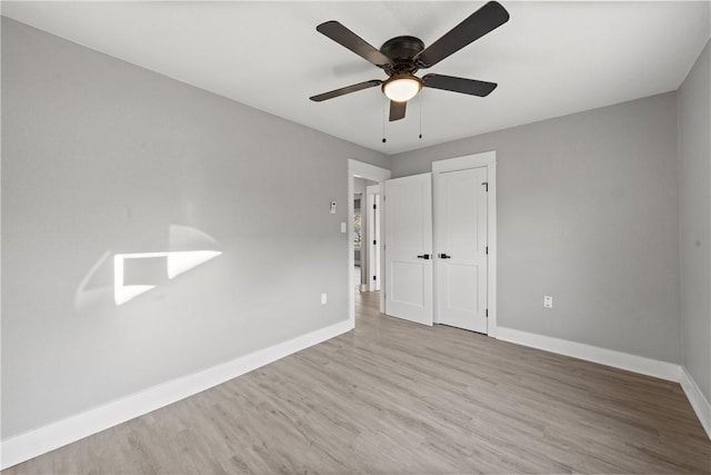 unfurnished bedroom featuring wood finished floors, a closet, baseboards, and ceiling fan