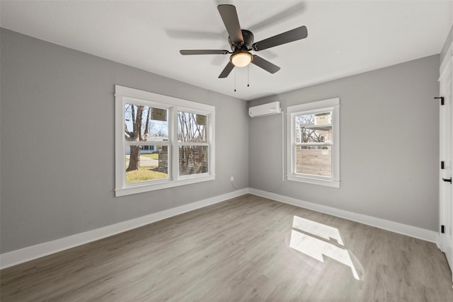 spare room featuring baseboards, wood finished floors, ceiling fan, and a wall mounted air conditioner