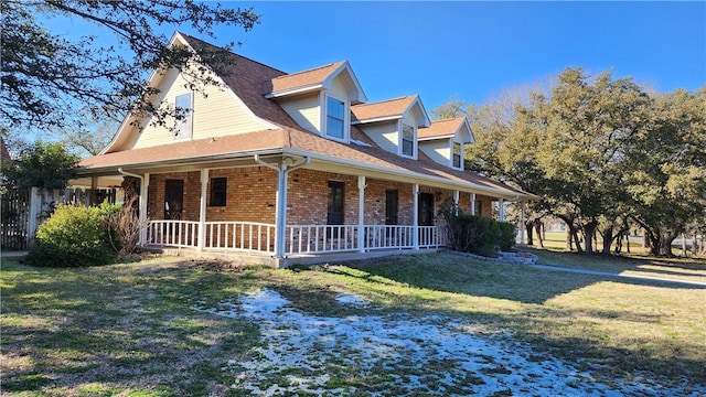 view of side of property with a yard, brick siding, and a porch