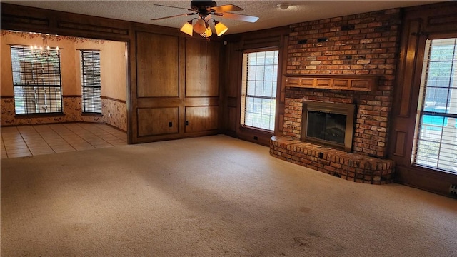 unfurnished living room featuring carpet floors, a textured ceiling, a brick fireplace, and plenty of natural light
