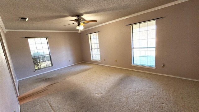 carpeted spare room featuring visible vents, plenty of natural light, a textured ceiling, and crown molding