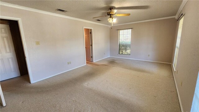 carpeted spare room with visible vents, a textured ceiling, ceiling fan, and ornamental molding