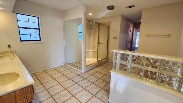 full bath with visible vents, double vanity, a sink, a shower stall, and tile patterned floors