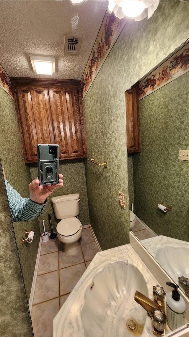 bathroom with tile patterned floors, toilet, visible vents, and a textured ceiling